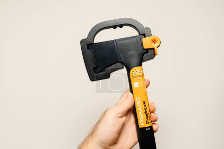 Photo for Paris, France - Nov 6, 2023: A male hand is displayed against a beige backdrop, holding a new Fiskars chopping axe, a robust tool for efficient gardening - Royalty Free Image