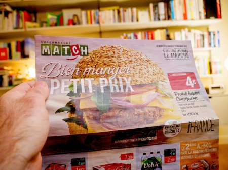 Foto de París, Francia - 12 de diciembre de 2022: Un hombre sostiene un anuncio del supermercado Match French, mostrando precios bajos especiales en varios alimentos, destacando la asequibilidad - Imagen libre de derechos