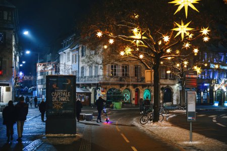 Photo for Strasbourg, France - Dec 19, 2022: Pedestrians in Strasbourg pass by an advertising board proclaiming the city as the Christmas capital, capturing the festive spirit - Royalty Free Image
