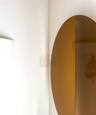 Foto de Un interior de lujo abstracto con un espejo dorado que refleja una lámpara con elementos decorativos, mostrando un diseño elegante - Imagen libre de derechos