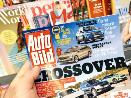 Photo for Frankfurt, Germany - Nov 10, 2023: A male hand holds an issue of Auto Bild, a German car magazine featuring reviews of the Opel Mokka, New Skoda Superb, and crossovers. - Royalty Free Image