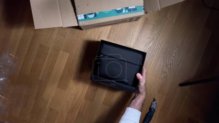 Photo for Paris, France - Sep 22, 2023: An overhead perspective shows a male hand unboxing the DJI Air 2S professional drone, along with its protective black pouch - Royalty Free Image