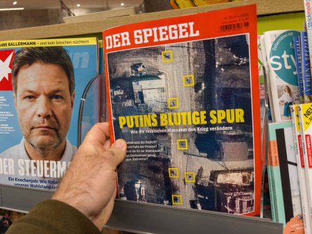 Foto de Frankfurt, Alemania - 14-abr-2023: Un hombre navega por las revistas en un quiosco de prensa de Frankfurt, con un enfoque en un número de Der Spiegel que presenta una historia sobre el impacto de Rusia en la guerra - Imagen libre de derechos