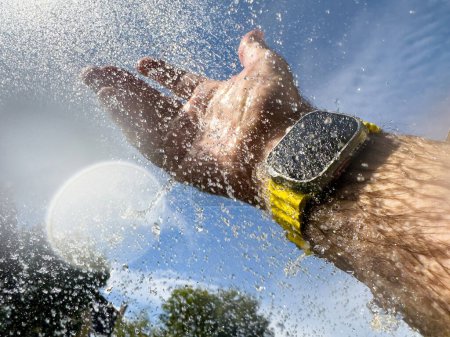 Photo for A smartwatch being splashed with water demonstrates its waterproof feature, emphasizing durability and technology in action. - Royalty Free Image