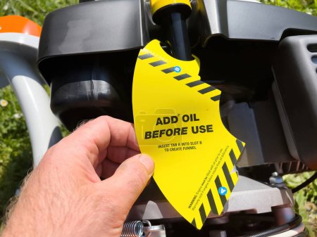 Foto de Una etiqueta amarilla vibrante en una nueva máquina aconseja agregar aceite antes de su uso, con instrucciones claras para crear un embudo - Imagen libre de derechos
