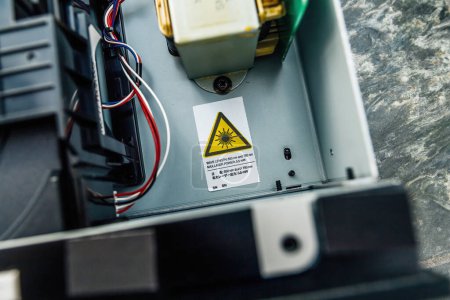 Foto de Imagen de un dispositivo láser con una pegatina de advertencia que indica el peligro, con cables y componentes visibles en el interior - reproductor de CD de alta fidelidad - Imagen libre de derechos