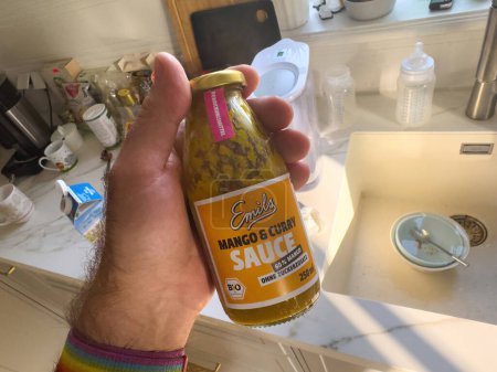 Photo for Frankfurt, Germany - Sep 29, 2023: POV of a male hand holding Emils Mango and Curry Sauce with 60percent mango content and a bio-organic German label in a kitchen. - Royalty Free Image