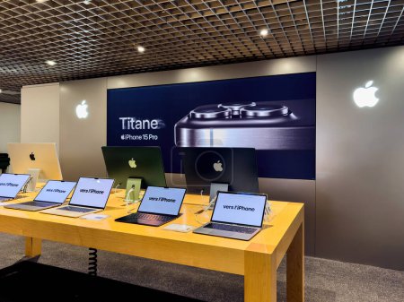 Téléchargez les photos : Paris, France - 3 oct. 2023 : MacBooks multiples avec texte en français et une grande affiche iPhone 15 Pro Titanium sur le mur à l'intérieur d'une boutique électronique Fnac - en image libre de droit