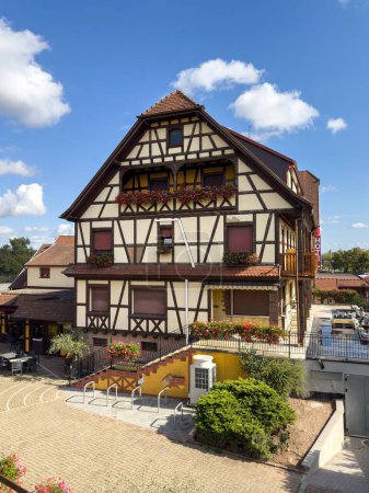 Photo for Aerial view of a timbered Alsatian house hotel, with a parking area in front and a large HVAC unit, showcasing the unique architecture - Royalty Free Image