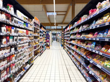 Photo for Paris, France - Nov 10, 2023: Perspective over a large supermarket aisle filled with multiple chocolates and candies, characterized by a tiled floor and an abundance of choices - Royalty Free Image
