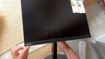 Photo for Paris, France - Feb 23, 2023: POV of a male hand pointing at the ThinkStation logotype on a new monitor during unboxing, emphasizing the brands identity - Royalty Free Image