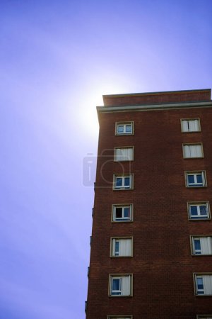 Téléchargez les photos : Vue en angle bas d'une grande maison en brique contre un ciel bleu et violet, symbolisant le concept d'air acide. - en image libre de droit