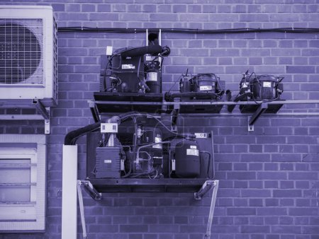 Téléchargez les photos : Thionville, France - 10 juin 2016 : l'ingénierie de précision de plusieurs compresseurs hermétiques situés à côté d'une thermopompe à air conditionné Daikin, parfaitement intégrée dans la façade d'une - en image libre de droit
