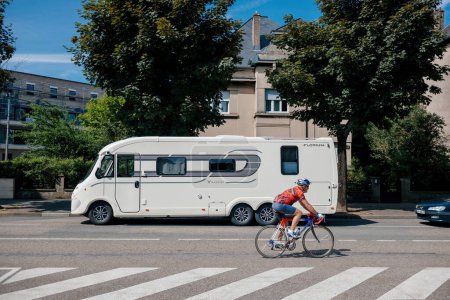 Foto de Thionville, Francia - 10 de junio de 2016: ciclista senior frente a Florium Winchester by Fleurette, un moderno vehículo recreativo que ofrece todas las funciones, estacionado en Thionville - Imagen libre de derechos