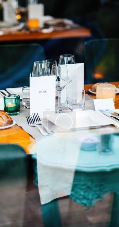 Foto de Recepción de la boda con el texto del menú que se muestra en una página blanca prístina, rodeado de platos bellamente decorados, tenedores y cristalería exquisita - Imagen libre de derechos
