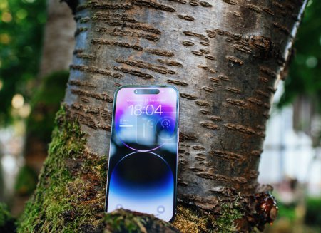 Foto de Londres, Reino Unido - 28 de septiembre de 2022: Un teléfono inteligente Apple iPhone 14 Pro ubicado en un cerezo, con una pantalla OLED y la exclusiva isla dinámica, que combina la tecnología con la naturaleza - Imagen libre de derechos