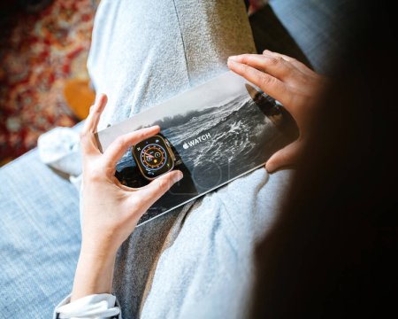 Photo for London, United Kingdom - Sep 28, 2022: point-of-view shot reveals a womans hand holding the package, unveiling the multiple bands of the new Apple Watch Series Ultra designed for extreme activities - Royalty Free Image