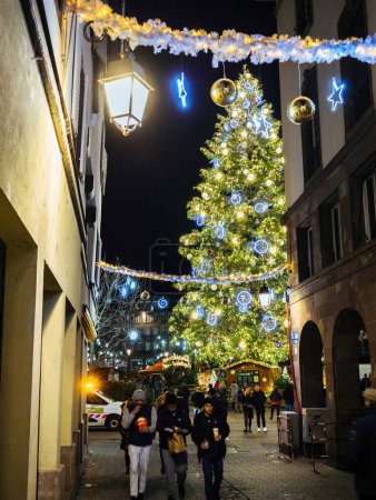 Téléchargez les photos : Strasbourg, France - 25 nov. 2022 : Vivez la magie des vacances avec une vue en angle bas sur un arbre de Noël imposant dans le centre de la place Kleber, encadré par la rue de lOutre, pendant que les gens profitent d'une - en image libre de droit