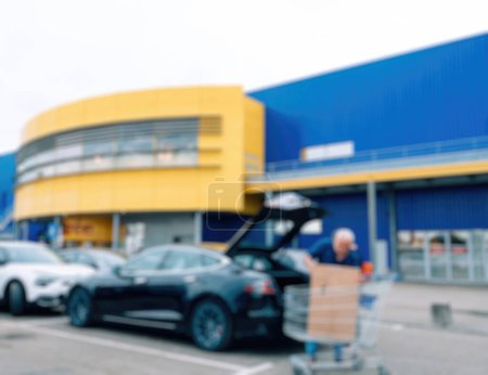 Téléchargez les photos : Paris, France - 31 août 2023 : Une vue déconcentrée capture un homme chargeant des meubles IKEA dans une voiture électrique Tesla dans le parking suédois des supermarchés de meubles. Témoin de la commodité de - en image libre de droit