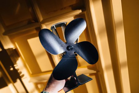 Téléchargez les photos : Main masculine tenant un ventilateur noir près d'une porte, améliorant la distribution de chaleur dans une pièce et réduisant la consommation de carburant de 15 % - en image libre de droit