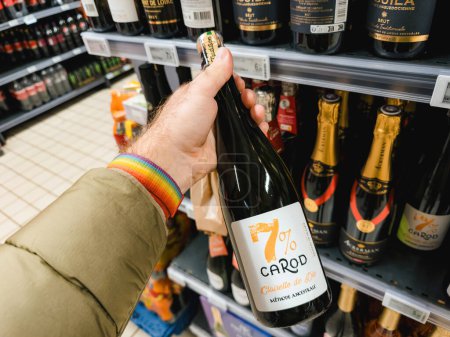 Photo for Paris, France - Nov 10, 2023: A male hand carefully chooses a bottle of 7percent Carod Clairette de Die, a traditional methode ancestrale wine, in the alcohol aisle of a supermarket - Royalty Free Image