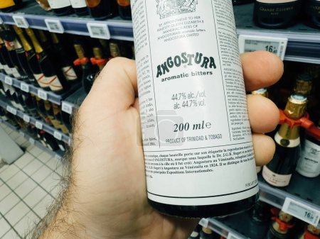 Photo for Paris, France - Nov 10, 2023: A POV shot captures a male hand selecting Angostura Aromatic Bitters with 44.7 percent alcohol, a product of Trinidad and Tobago - Royalty Free Image