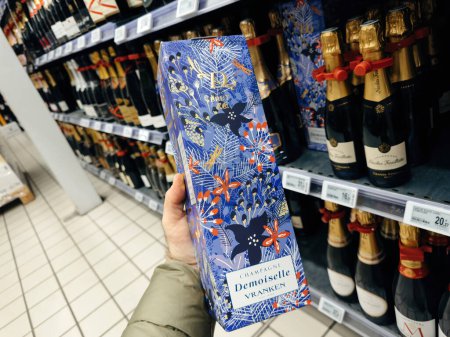 Foto de París, Francia - 10 de noviembre de 2023: Una mano masculina selecciona un lujoso paquete de champán francés Demoiselle Vranken en un supermercado, que representa una selección de alcohol de alta gama - Imagen libre de derechos