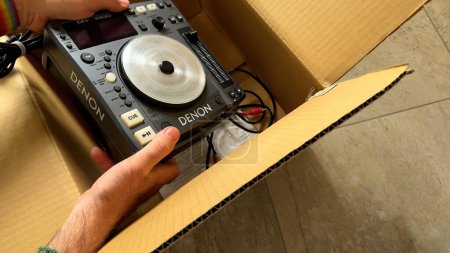 Photo for Paris, France - Jun 10, 2023: POV shot of a male hand unboxing the new Denon DN-S1000 DJ equipment from its cardboard packaging, revealing its features and components - Royalty Free Image