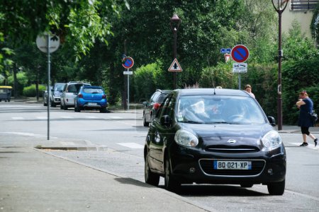 Téléchargez les photos : Strasbourg, France - Aug 12, 2022: Urban street lined with cars parked under the shade of lush trees, complete with road signage and the bustle of city life. - en image libre de droit
