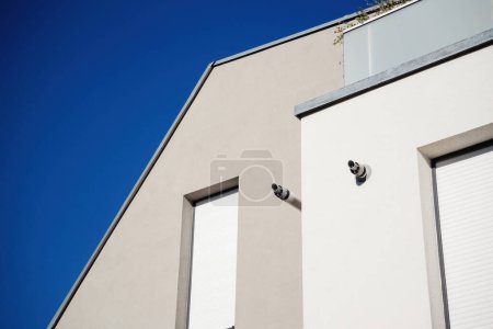 Foto de Modern building facade with clean lines, contrasting against a clear blue sky, featuring gas boile chimneys and closed shutters - Imagen libre de derechos