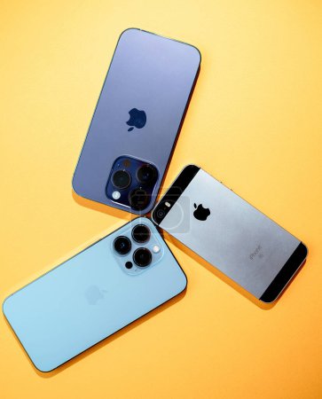 Photo for Paris, France - Sep 29, 2022: A collection of three iPhone models - SE, 11 Pro, and 12 Pro, displayed with cameras aligned, set against a vivid yellow background. - Royalty Free Image