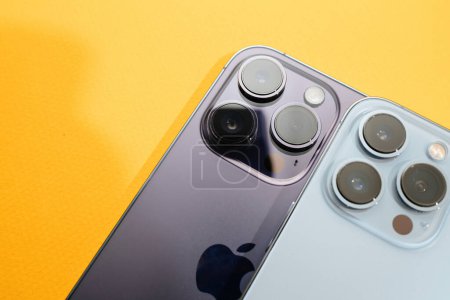 Téléchargez les photos : Paris, France - Sep 29, 2022: A close-up view of two luxury Apple iPhone models, 13 Pro and 14 Pro, placed side by side against a yellow background, highlighting their features - en image libre de droit