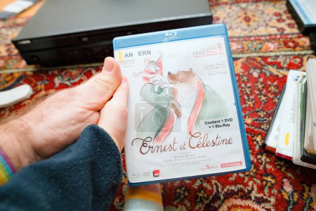 Téléchargez les photos : Paris, France - Dec 16, 2023: POV of a father showing a new DVD with Ernest and Celestine characters to his toddler, introducing them to new stories - en image libre de droit