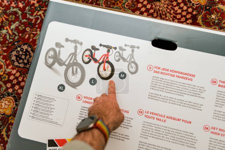 Foto de Múnich, Alemania - 8-abr-2023: Un dedo de las personas señala las bicicletas de diferentes tamaños en una guía de tallas, indicando cómo seleccionar la correcta. - Imagen libre de derechos