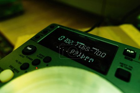 Foto de Una configuración de DJ profesional bajo un elenco de color verde, que muestra el código de tiempo en minutos y segundos, destacando la complejidad del proceso de mezcla - Imagen libre de derechos