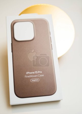 Foto de París, Francia - 25 de octubre de 2023: Un iPhone 15 Pro encerrado en una cubierta finamente tejida sobre un fondo de círculo dorado, capturado a través de una lente de desplazamiento basculante para una perspectiva única. - Imagen libre de derechos