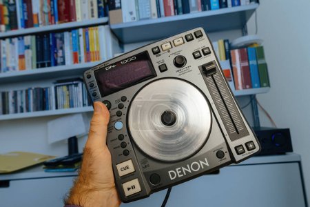 Foto de París, Francia - 24 de octubre de 2023: Acercamiento de una configuración de ajuste de la mano en un reproductor de CD Denon DJs contra una estantería Vitsoe - Imagen libre de derechos