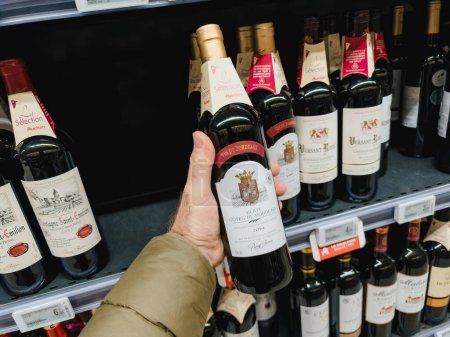 Foto de París, Francia - 10-nov-2023: Un punto de vista masculino mientras toma la última botella de 2019 Red Blaye Cotes de Bordeaux del estante, comprando vinos para fiestas navideñas - Imagen libre de derechos