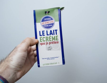 Téléchargez les photos : Paris, France - 20 déc. 2023 : Vue à la première personne d'une main tenant un paquet de 1 litre de lait Laiterie Verneuil Touraine-Berry, fabriqué en France. - en image libre de droit