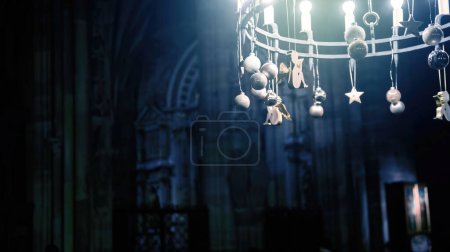Téléchargez les photos : Une photographie faiblement éclairée capture un lustre orné de figures et d'étoiles, accroché à l'intérieur d'une cathédrale avec des éléments d'architecture gothique. - en image libre de droit