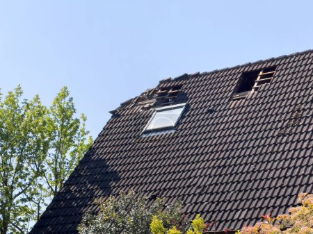 Foto de Vista de un techo de la casa dañado con agujeros visibles y azulejos faltantes, lo que indica una necesidad de reparaciones urgentes. - Imagen libre de derechos