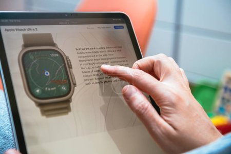 Foto de Londres, Reino Unido - 13 de septiembre de 2023: Una mujer lee de cerca la información más reciente sobre el nuevo Apple Watch Ultra A2 en su iPad, en una fotografía detallada de cerca - Imagen libre de derechos