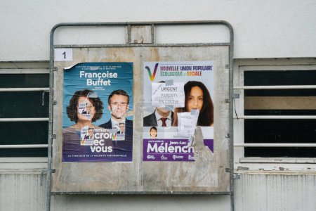 Téléchargez les photos : Strasbourg, France - 19 juin 2022 : Un assortiment d'affiches de campagne électorale usées et déchirées est affiché sur un panneau métallique contre une façade d'un bâtiment urbain. - en image libre de droit