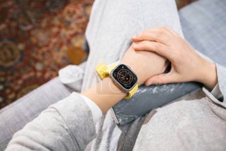 Photo for London, United Kingdom - Sep 28, 2022: A woman showcasing her newly unboxed and set-up Apple Watch Ultra 2, with a vibrant yellow strap on her wrist. - Royalty Free Image