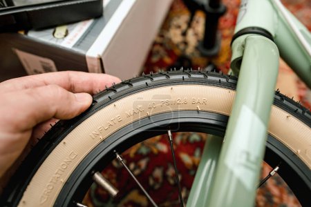 Téléchargez les photos : Vue détaillée d'une main de personne sur un pneu de bicyclette, mettant en évidence les spécifications techniques en relief et la pression de gonflage maximale. - en image libre de droit