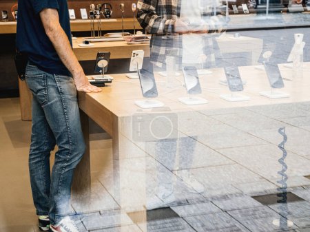 Téléchargez les photos : Paris, France - 22 sept. 2023 : Un Apple Store Genius, près d'une table avec plusieurs iPhones, guide un client dans le choix de l'appareil parfait. Assistance d'experts pour des choix éclairés - en image libre de droit
