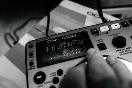Téléchargez les photos : Paris, France - 24 oct. 2023 : Une main masculine sur le nouvel équipement de mixage Denon DN-S1000 DJ, testé au rythme 095 BPM après le déballage, dans une scène en noir et blanc - en image libre de droit