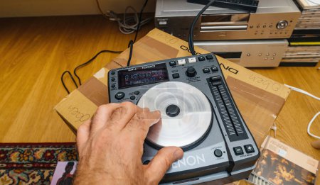 Téléchargez les photos : Paris, France - 24 oct. 2023 : Regarder un DJ expérimenté utiliser le mélangeur Denon DN-S100, mélangeant sans effort de vrais disques CD dans un affichage fascinant de l'art du DJing en action - en image libre de droit