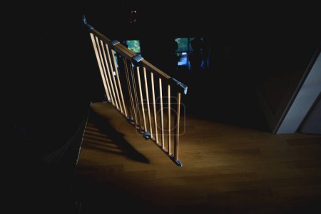 Téléchargez les photos : Une vue aérienne captivante d'une barrière d'escalier en bois dans une maison de luxe. Les rayons du soleil illuminent le couloir sombre, créant une atmosphère chaleureuse et accueillante - en image libre de droit