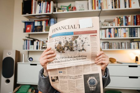 Foto de Frankfurt, Alemania - 20 de diciembre de 2023: El titular del Financial Times sobre Zelenskys en busca de fondos cautiva a una mujer que lee en una lujosa sala de estar, destacando problemas globales - Imagen libre de derechos